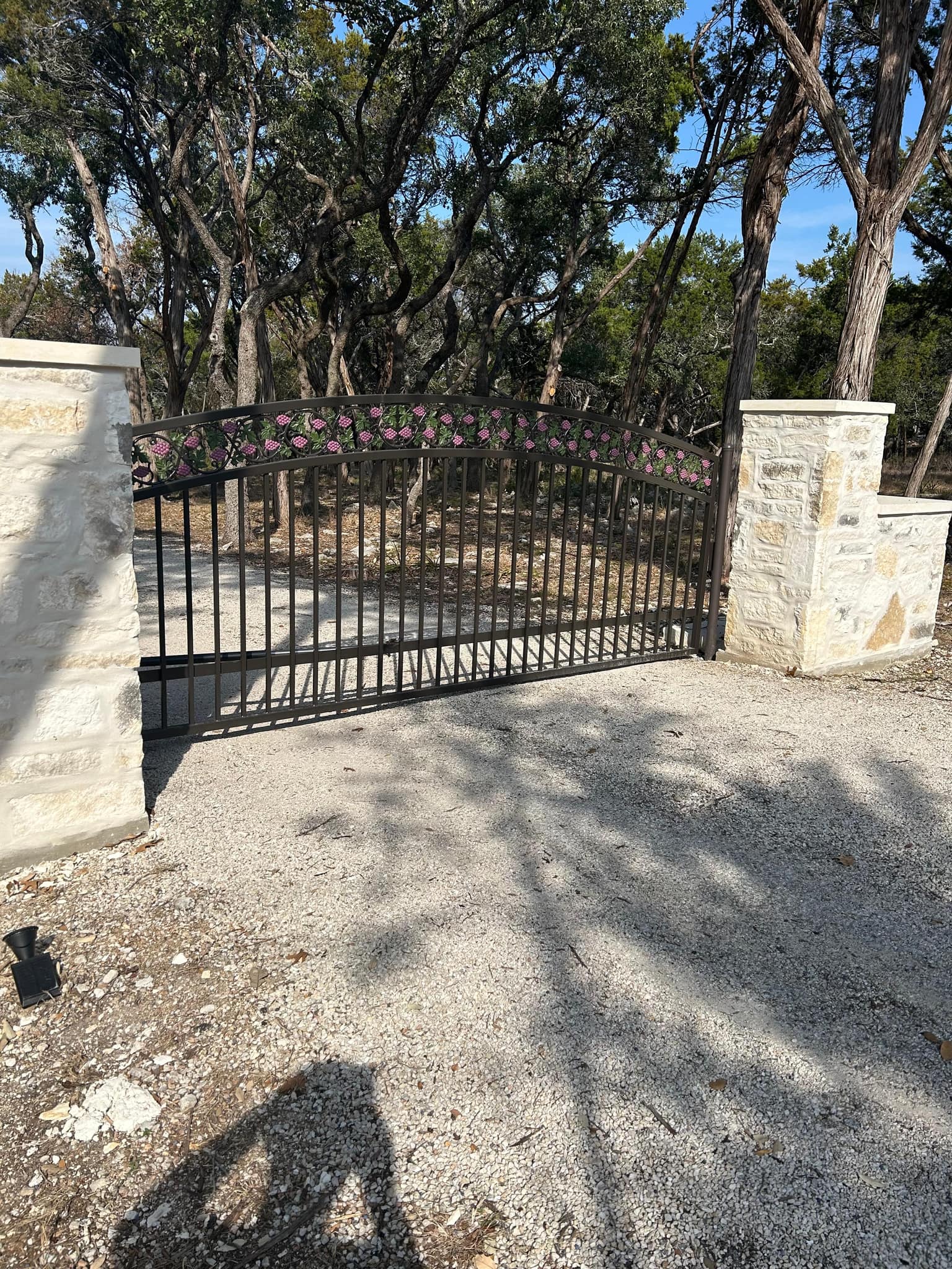 Arched iron driveway gate between limestone pillars