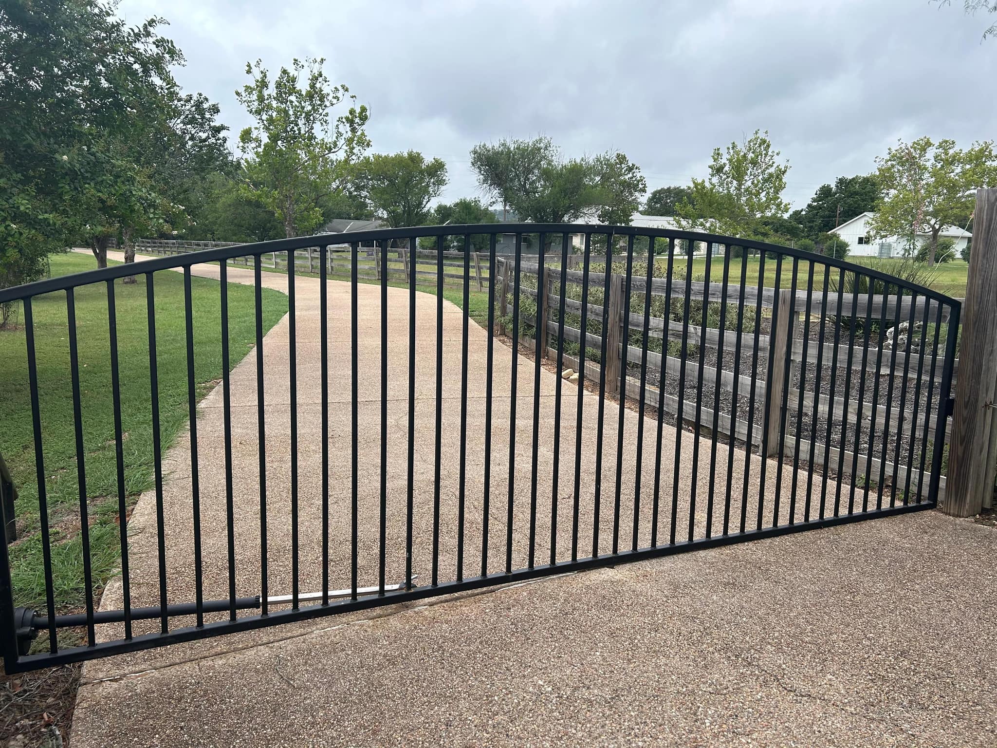 Arched black iron gate across a long driveway
