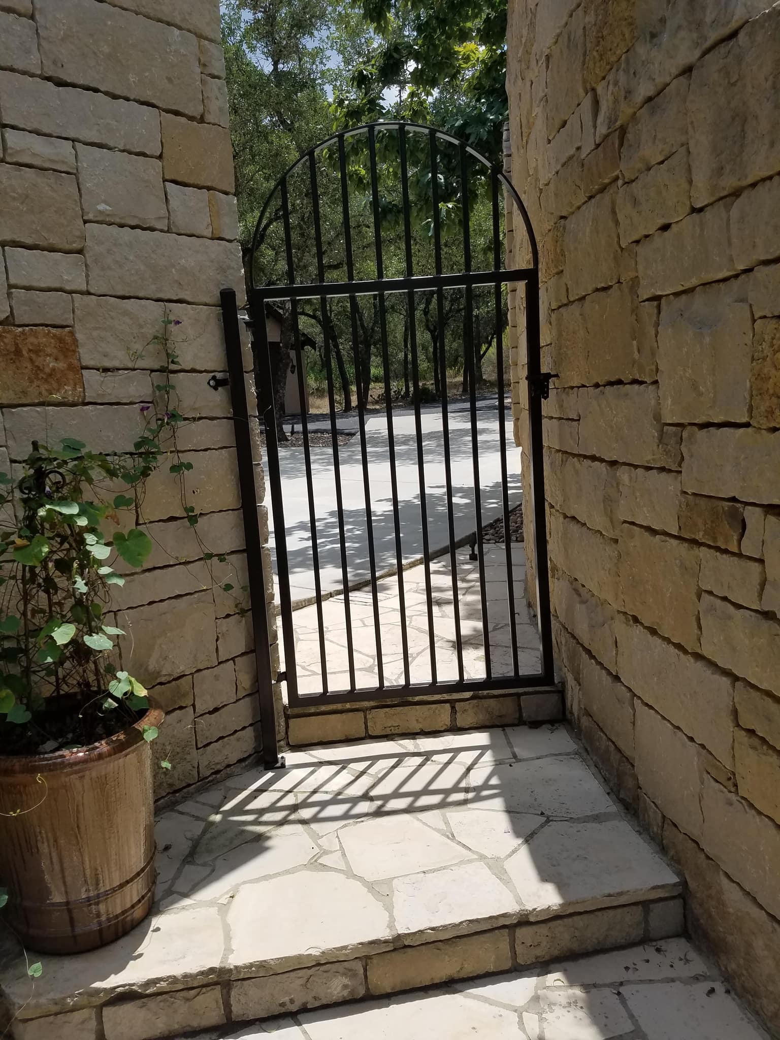 Arched iron walk gate between two stone walls