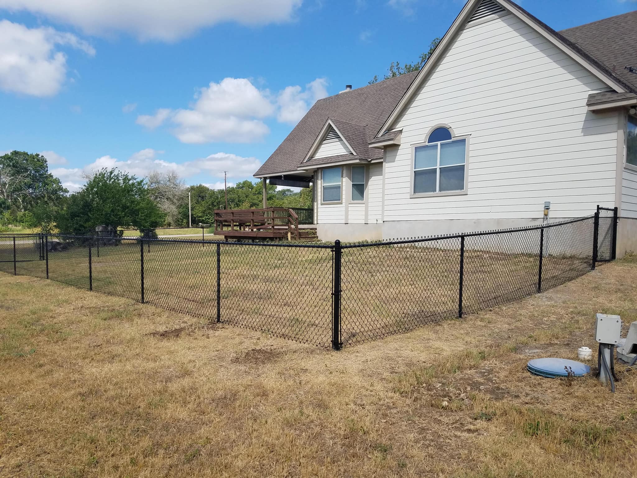 Black chain link fence around the side yard of a house