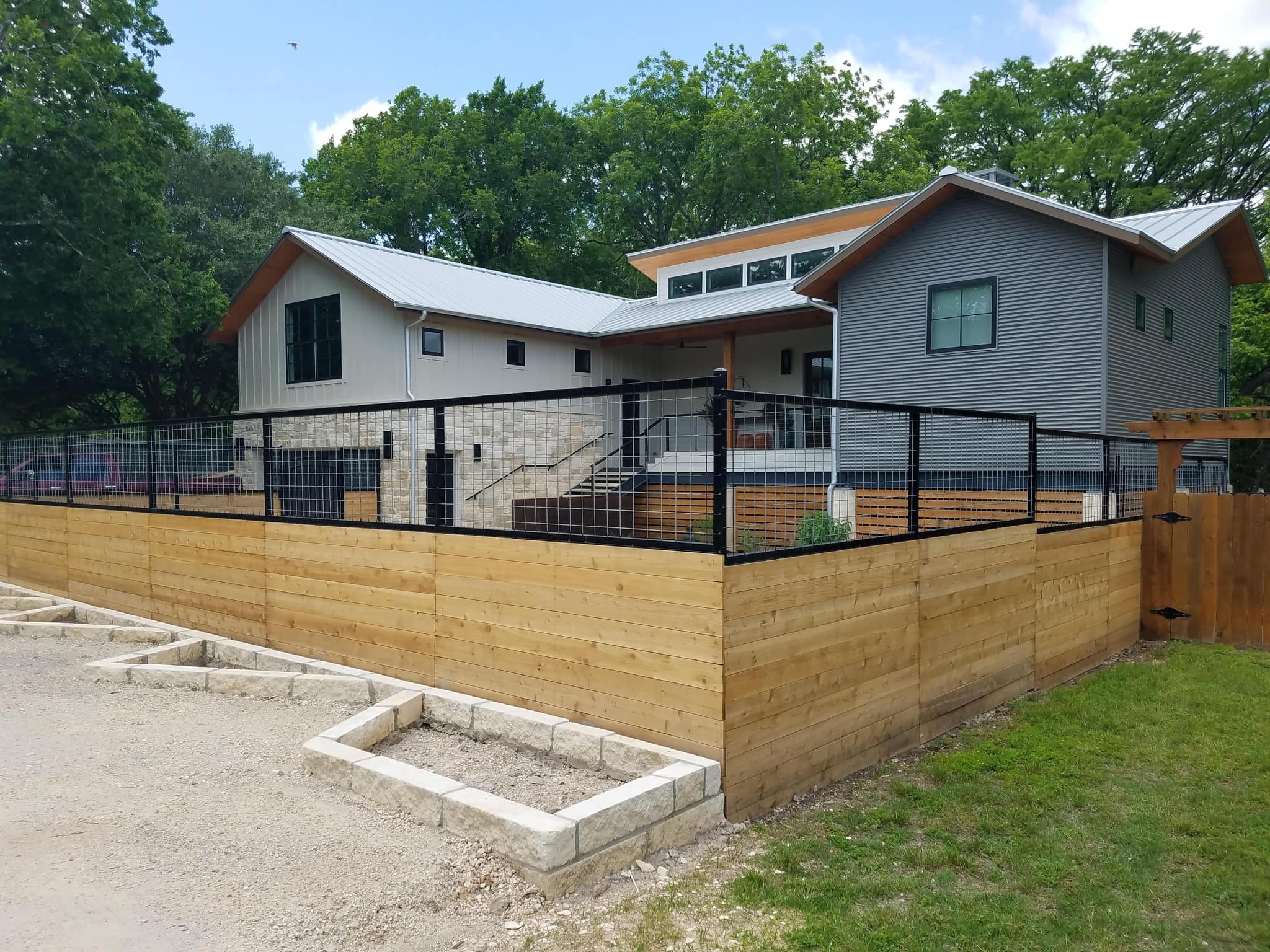 Horizontal cedar lower fence topped with black welded-wire panels around a modern home