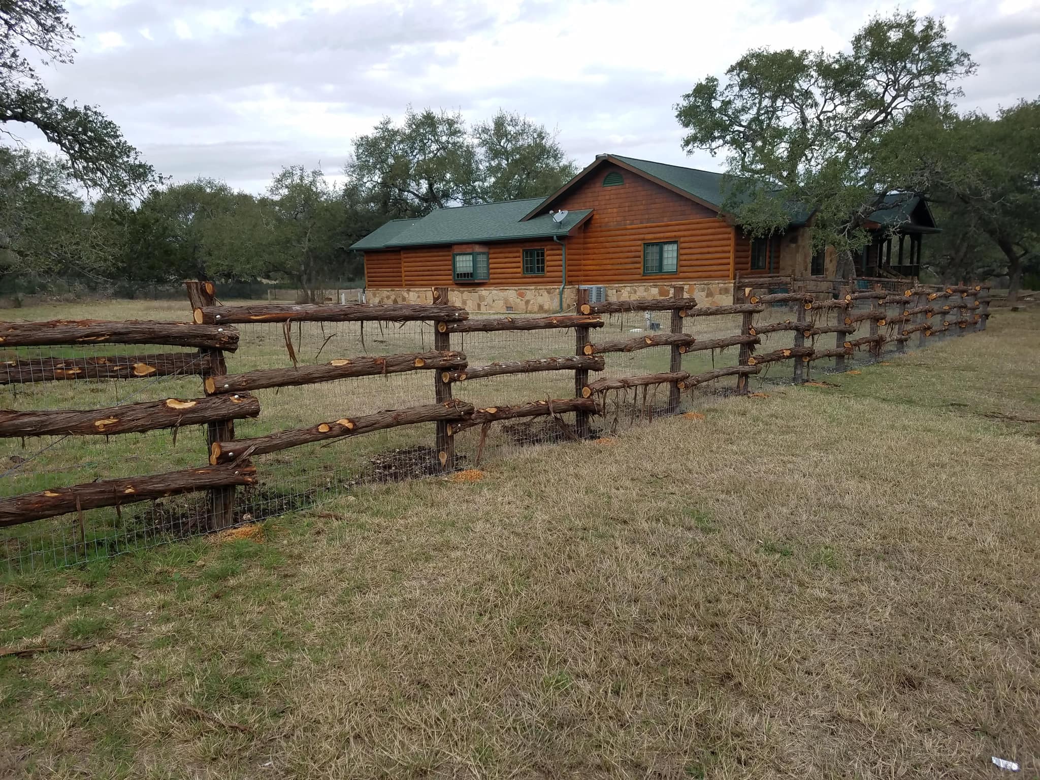 Rustic cedar log rail fence in front of a log home