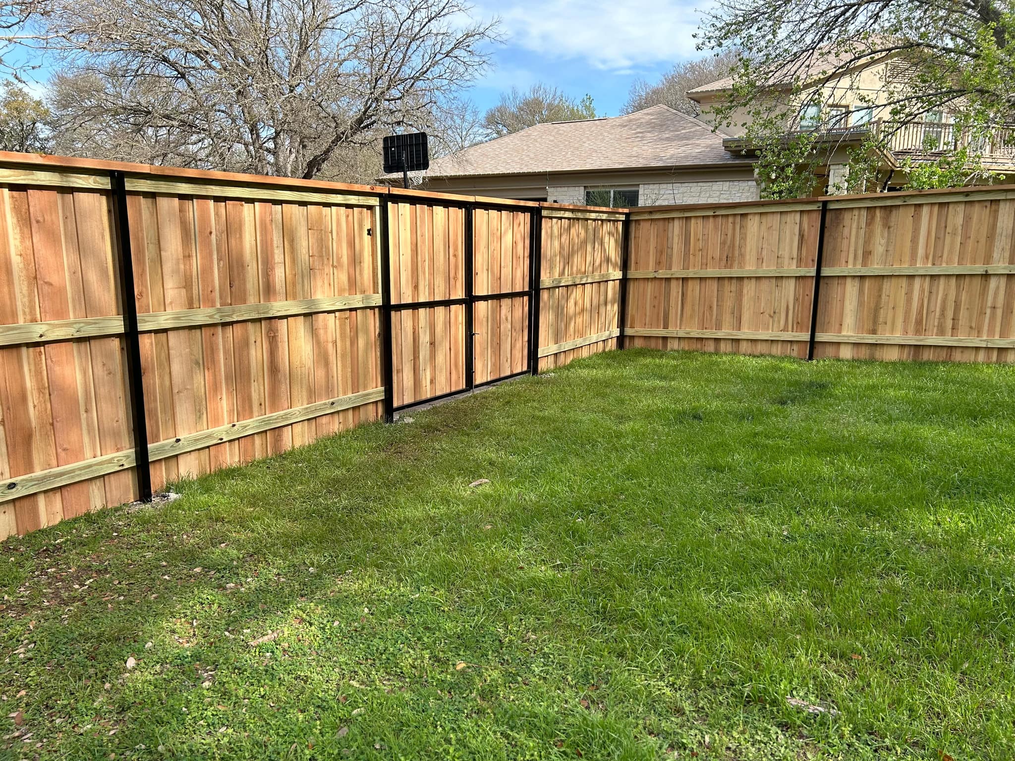 Cedar privacy fence on black steel posts around a backyard lawn