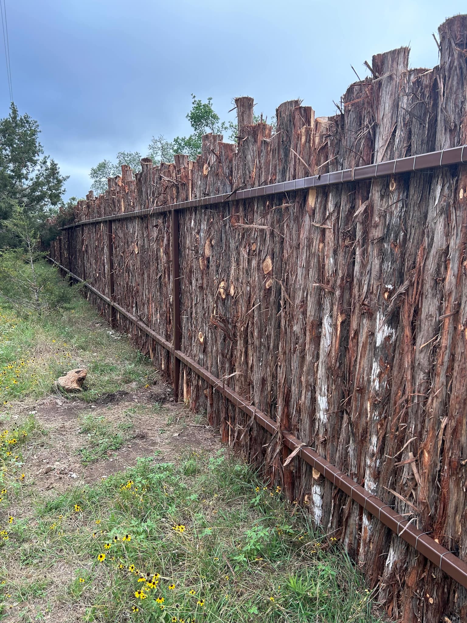 Rough cedar stake coyote fence on steel rails