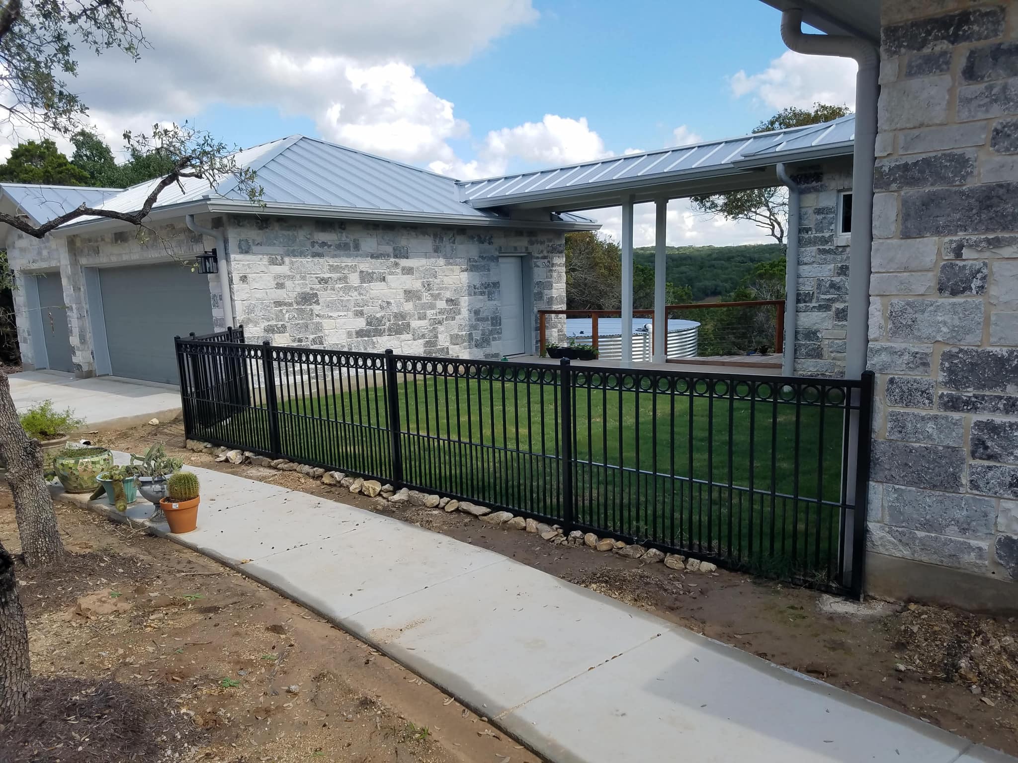 Black iron fence enclosing a lawn beside a stone house