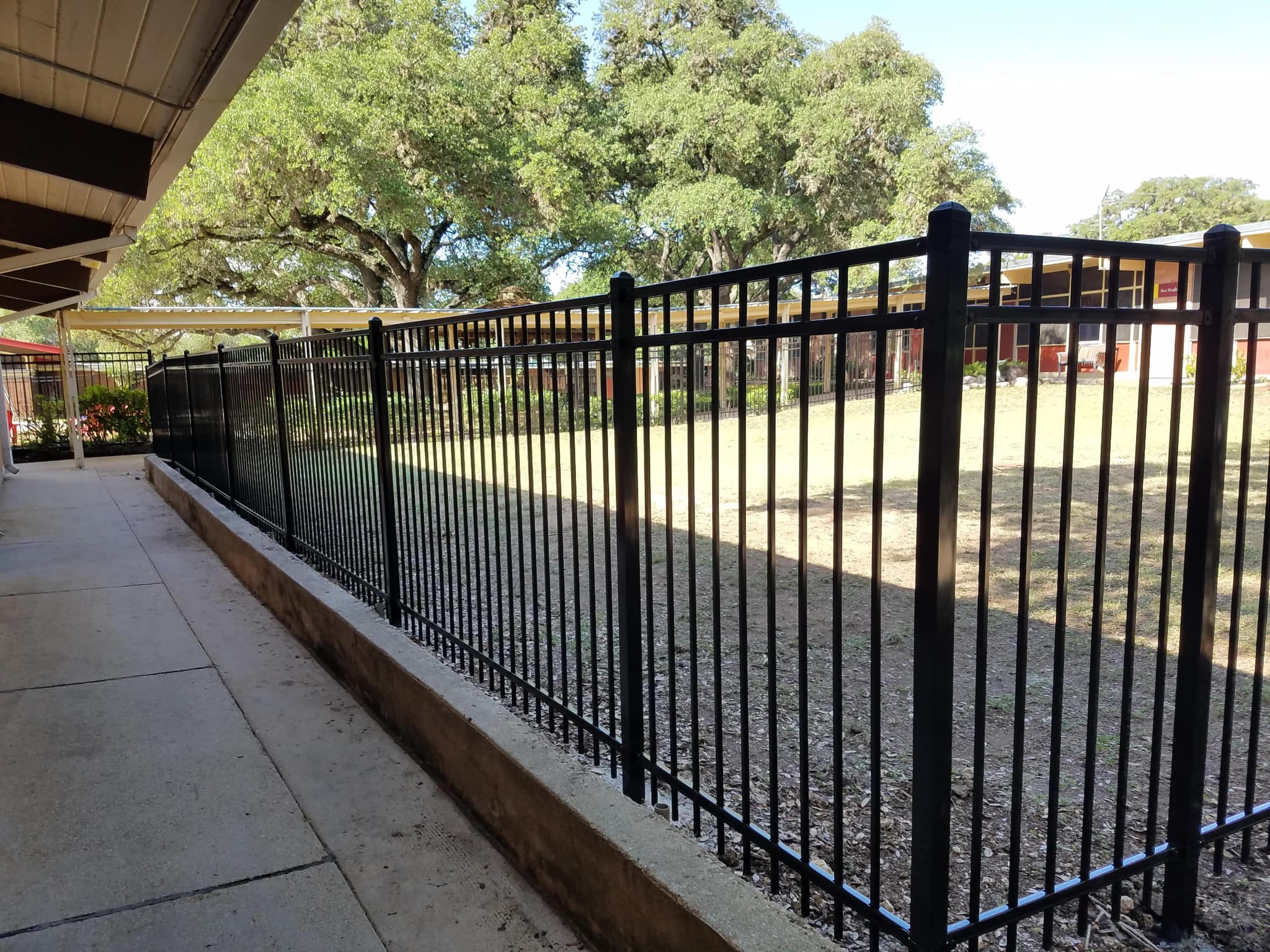 Black iron fence on a low curb beside a covered walkway