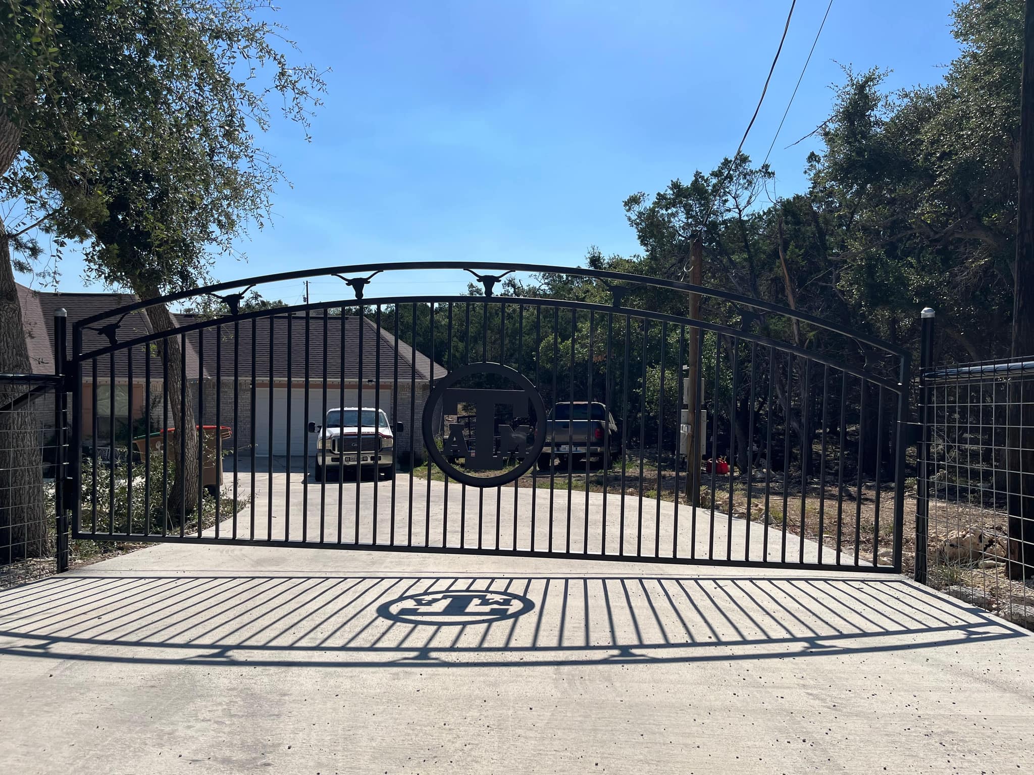 Arched iron driveway gate with a round monogram medallion