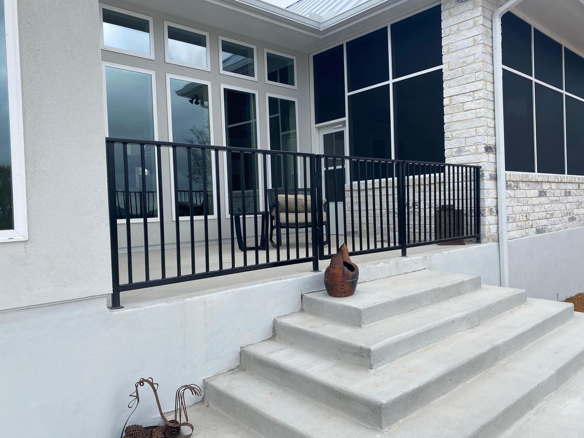 Black iron railing along a raised front porch above concrete steps