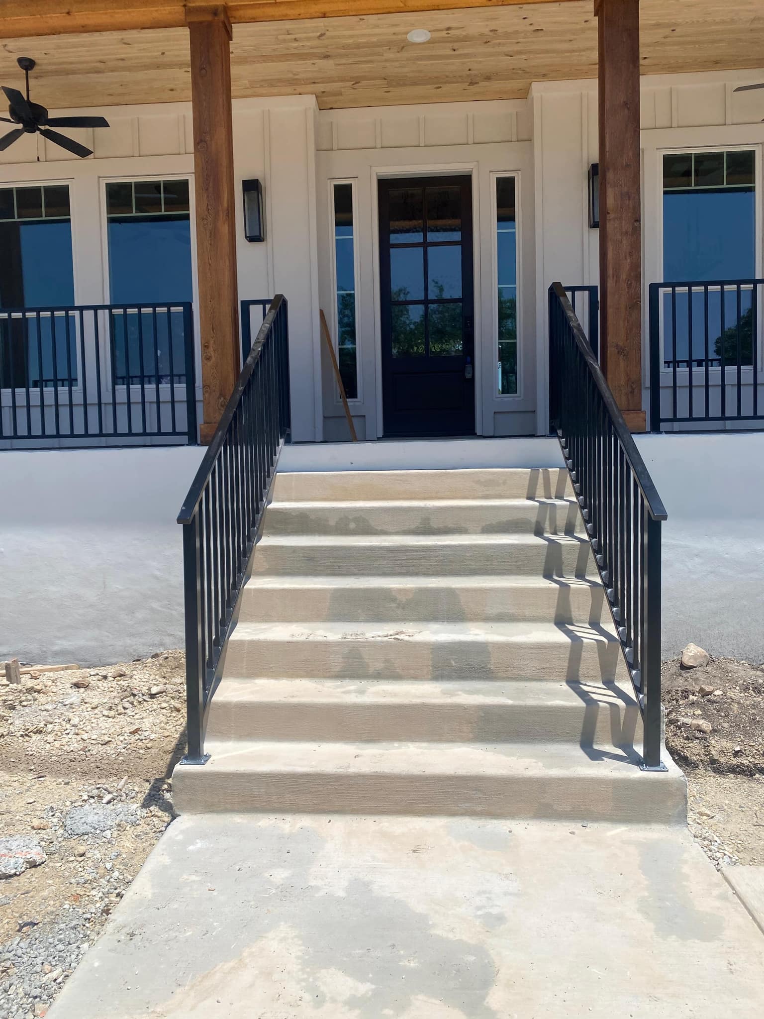 Black iron porch railing and stair rails on a white farmhouse