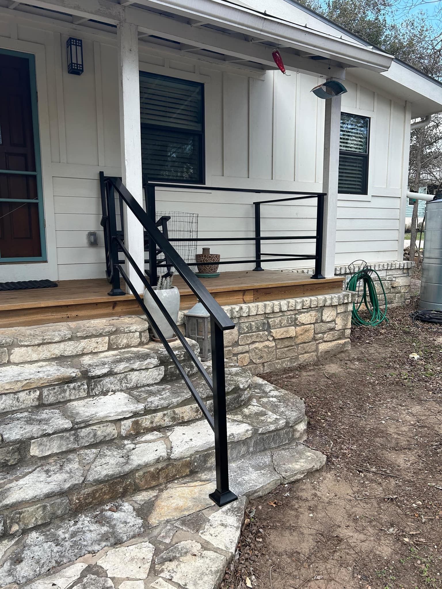Black square-tube handrail down limestone steps, with matching railing along the front porch