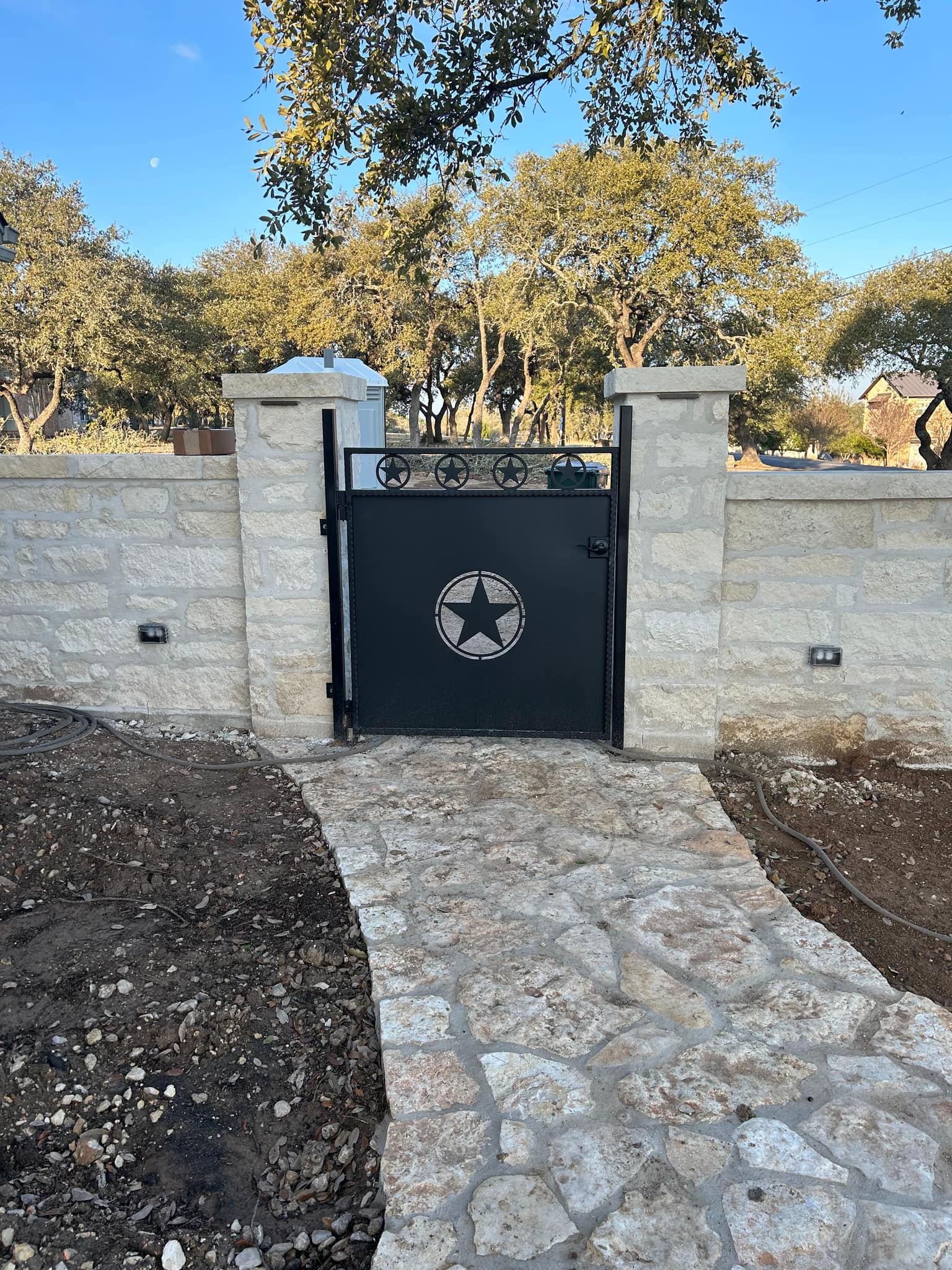 Solid black walk gate with a cut-out star, set in a stone wall