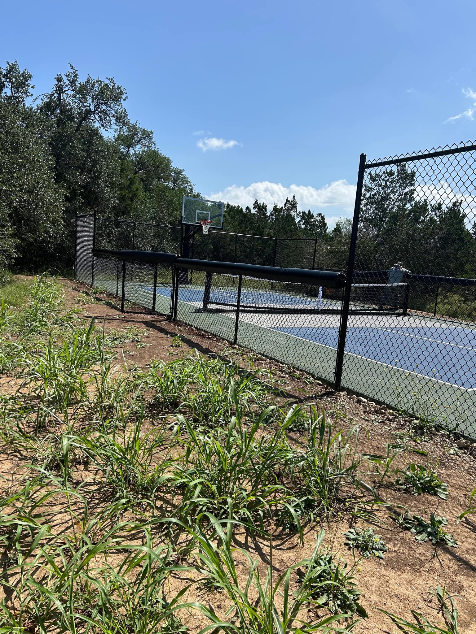 Black chain link fence around a sport court with a basketball hoop