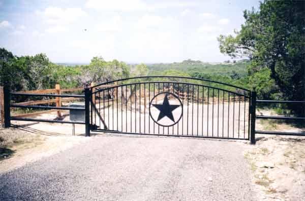 Black iron driveway gate with a Texas star, looking out over the Hill Country