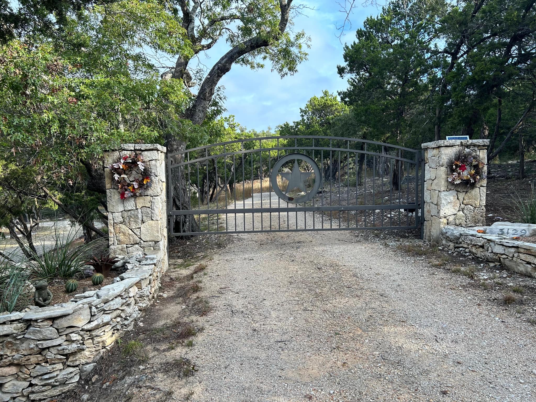 Iron driveway gate with a star medallion between stone columns