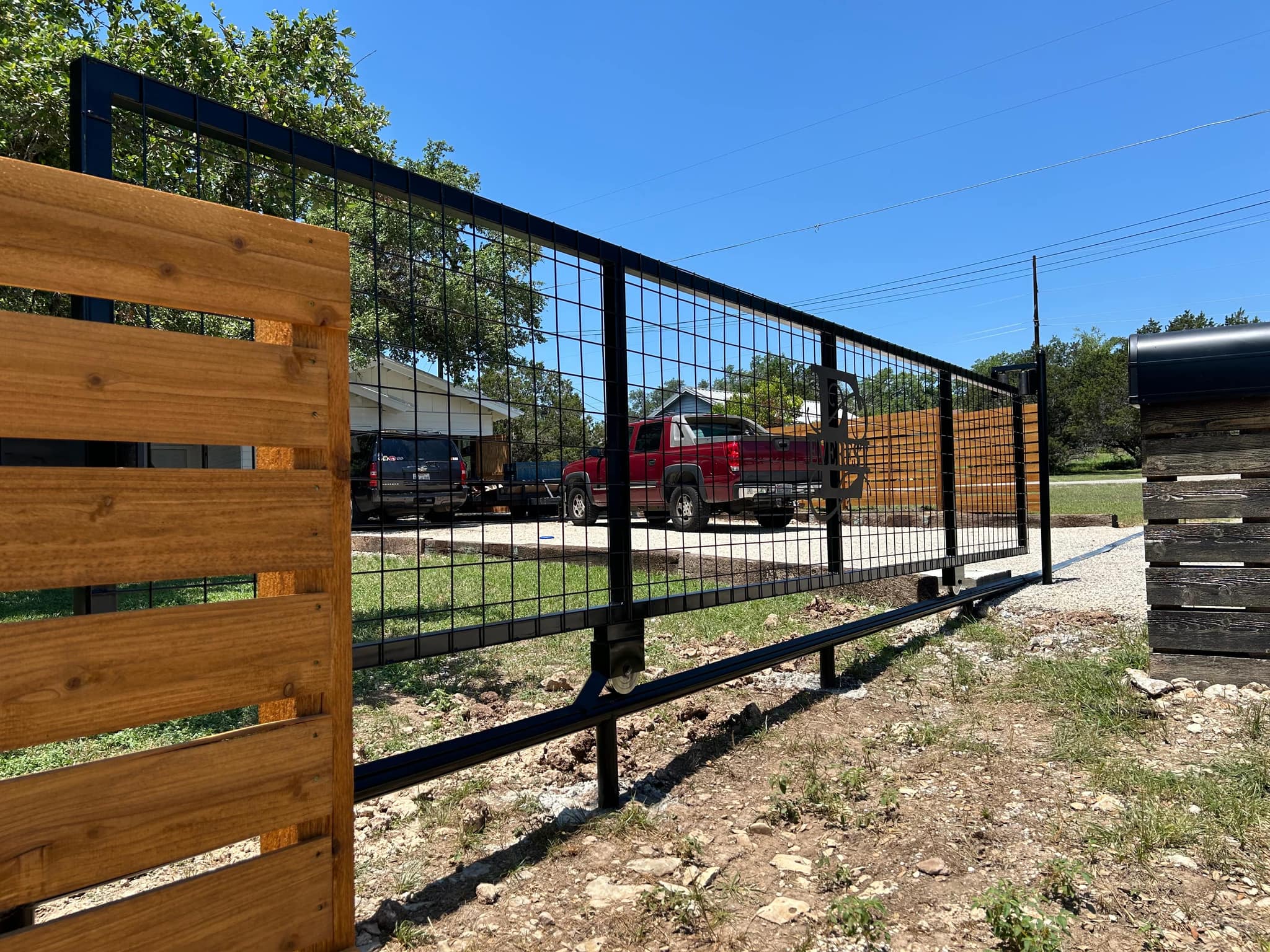 Black-framed welded-wire slide gate beside a horizontal cedar panel